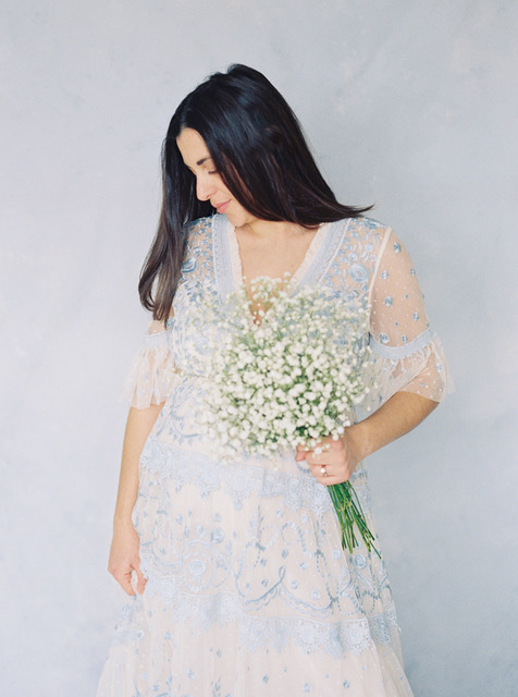 Woman in white floral dress posing for maternity photoshoot