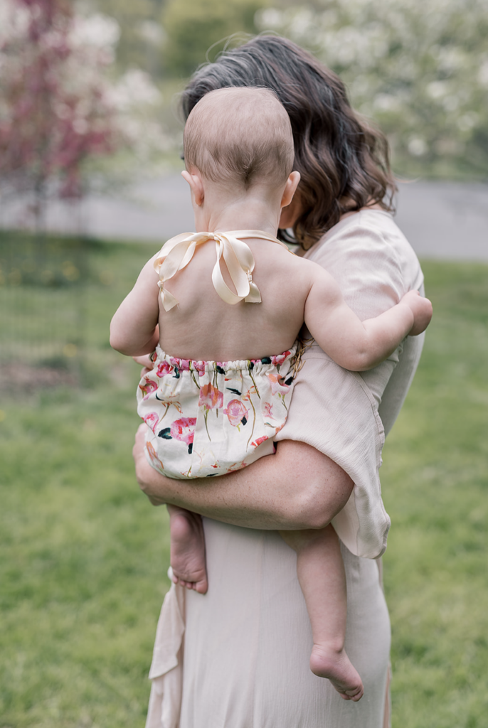 Mother holding baby in floral romper, how to prepare for your family photo session with Norabloom